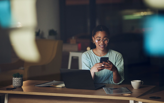 Woman in dark office with phone, typing or reading email, message or social media post connectivity. Late night at work, cellphone and girl at desk networking, online chat or writing text at overtime