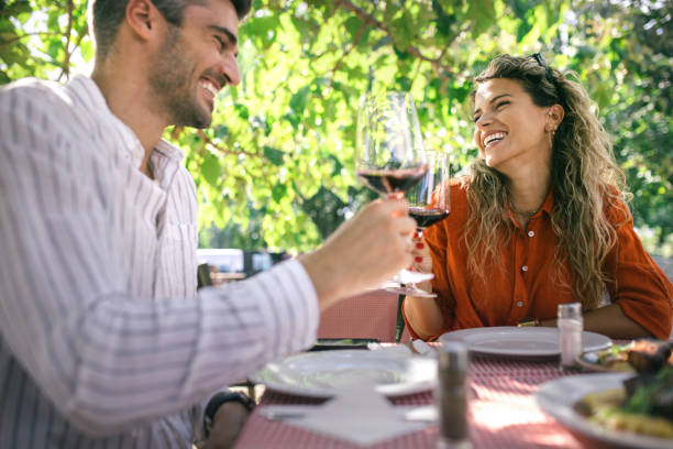 istock a young couple is using a mobile phone while having lunch and drinking wine 1674071462