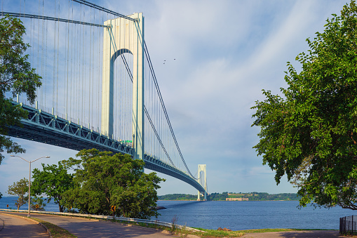 High resolution stitched image of the Verrazano-Narrows Bridge on a spring morning. The bridge connects boroughs of Brooklyn and Staten Island in New York City. It was built in 1964 and is the largest suspension bridge in the USA. Historic Fort Wadsworth is next the bridge foot. Canon EOS 6D full frame censor camera. Canon EF 50mm f/1.8 II Prime Lens. 3:2 Image Aspect Ratio. The image was stitched from 2 rows of images. This image was downsized to 50MP. Original image resolution is 69MP or 10206 x 6804 px.