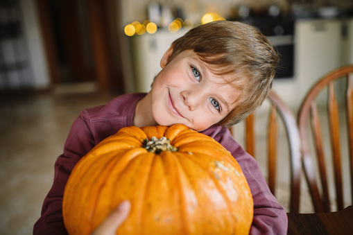 Happy child playing with pumpkin on Halloween in Autumn