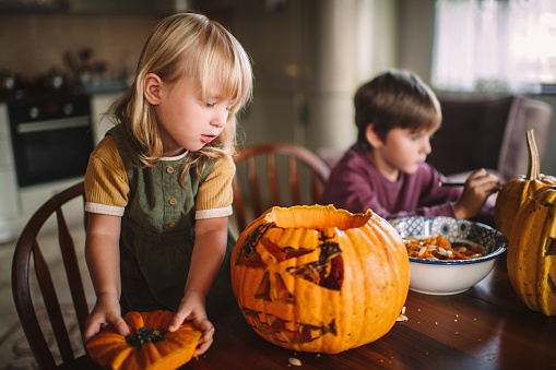 Happy children carving pumpkins on Halloween in autumn