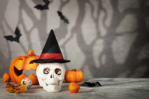 Halloween holiday concept with scull wearing witch hat. Minimal surreal creative concept for Halloween celebration banner or advertisement. Halloween background, copy space