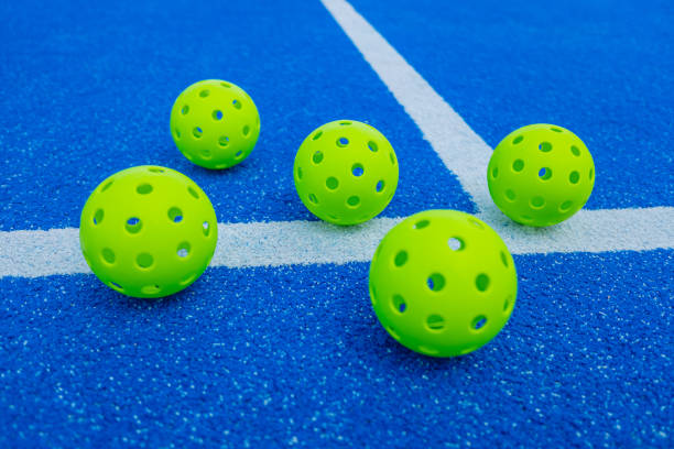 istock Five pickleball balls next to a blue court line 1674096365
