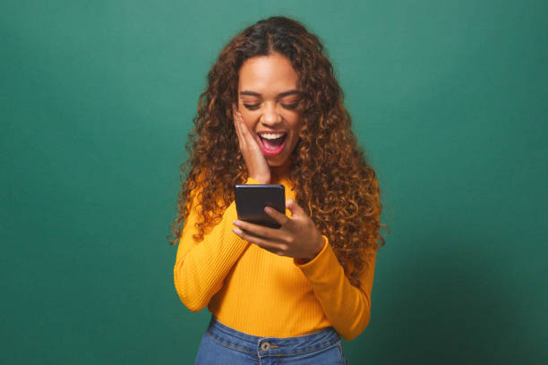 istock Young biracial woman reads text message shocked excited, green studio background 1674137366
