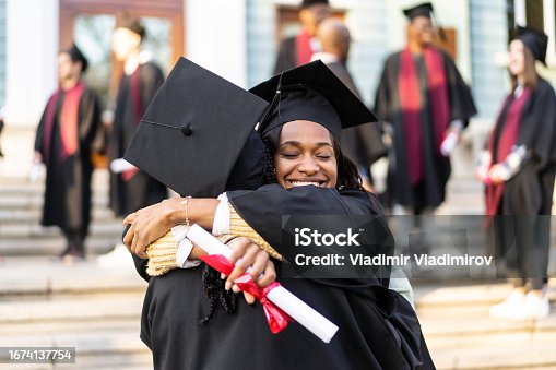 istock Two female graduates embracing each other 1674137754