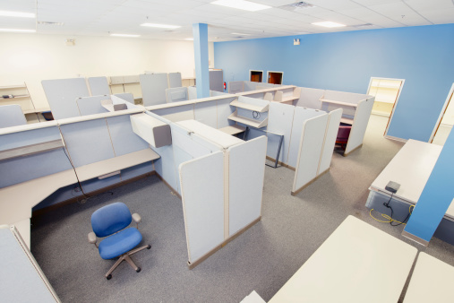 This is a wide angle, horizontal, color photograph of an empty office divided up into cubicles.