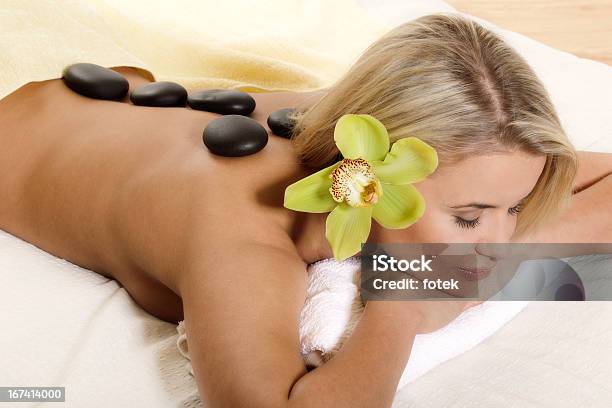 Woman Relaxing With Flower And Hot Stones Stock Photo - Download Image Now - 2011, Adult, Adults Only