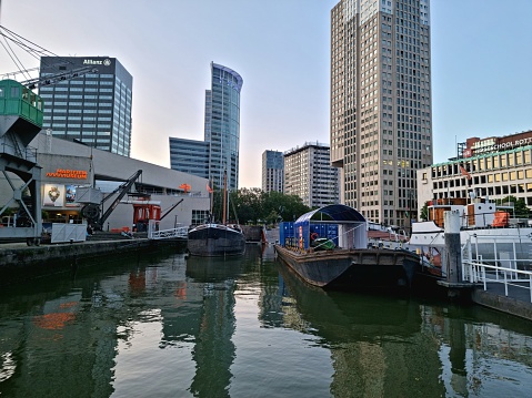 The Leuvehaven is located in the Maritime District. It is the oldest part of Rotterdam harbor. The image shows several historic nautical vessels during evening.