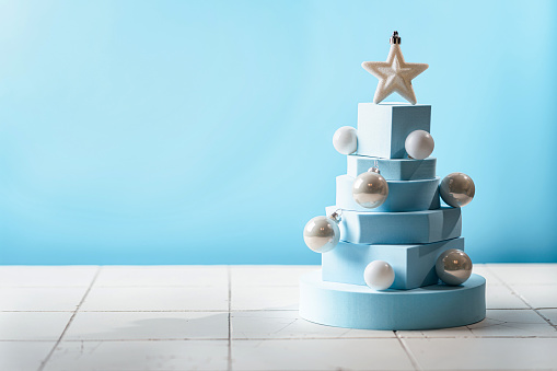 Christmas tree made of blue geometric shapes and podiums on blue background