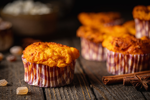 Sweet homemade cottage cheese muffins with pumpkin on dark wooden background