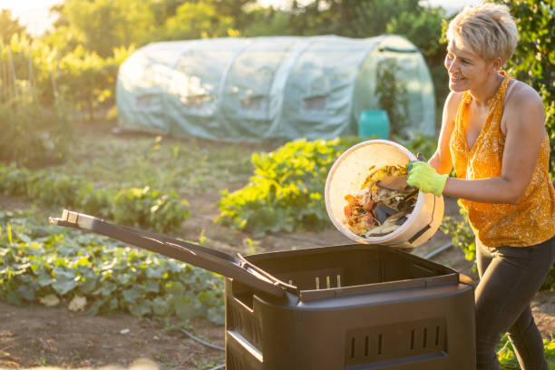 una mujer vaciando los residuos de comida en un compostador de jardín en casa - green thumb refrán en inglés fotografías e imágenes de stock