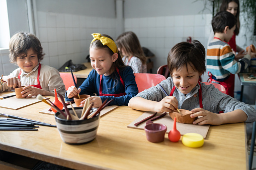 School pupils are concentrating on using modelling toold to shape their clay in a craft lesson at school