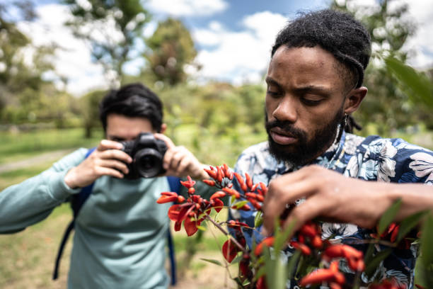 Young man and his friend photographing flowers outdoors