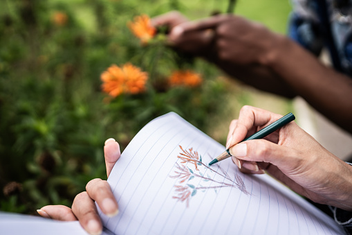 Close-up of a woman drawing flowers in her notepad