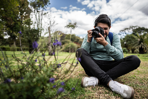 Young man photographing flowers outdoors
