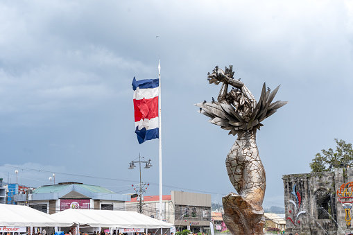 Beautiful View of the Costa Rica Flag with the Bicentennial Angel in Cartago, next to the Ruins and the basilica - Costa Rica Patriotic Symbols
