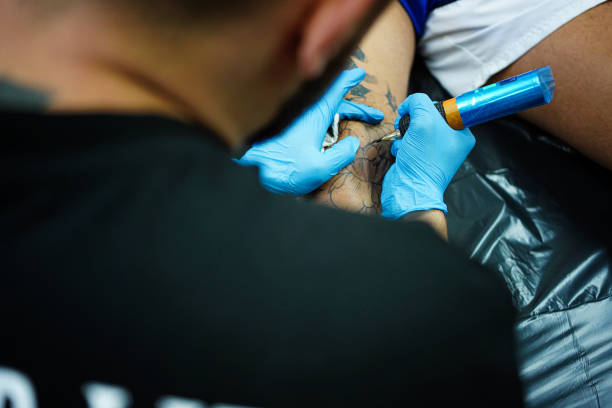 istock Tattoo artist tattooing customer leg in studio 1674183343