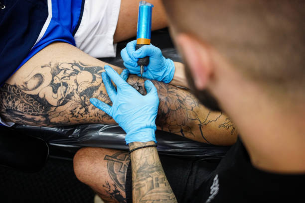 istock Young adult man tattooing man's leg in studio 1674183687