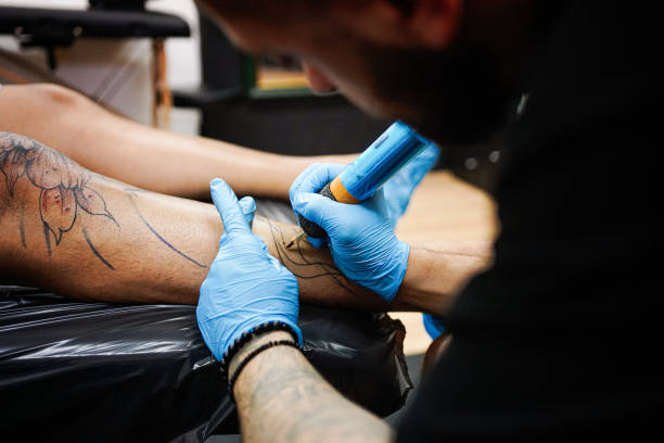 istock Tattoo artist tattooing a man's leg in studio 1674184274