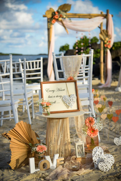 A decorated wedding arch stands on the sandy beach in Seychelles, with the ocean and lush landscape beautifully complementing the setting.