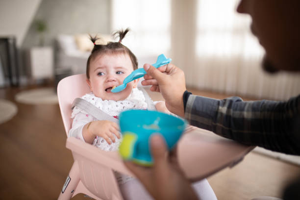 istock Baby girl looking away while being fed by her father 1674197669