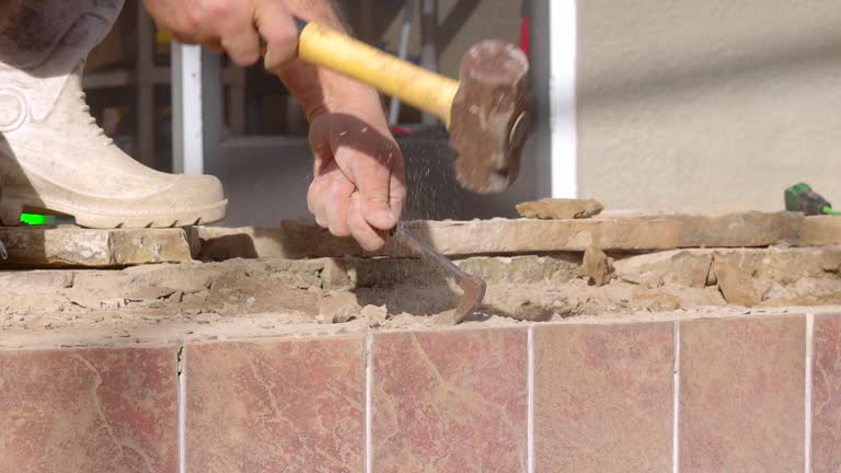 Man Refinishing the Edge of Pool - Hammering Ground to Reseal Flagstone - Close Up