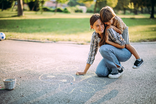 Mother and son draw with chalk on the concrete