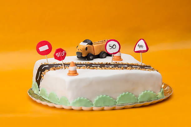 Two tier tall cake with fondant truck and road decoration on  orange background