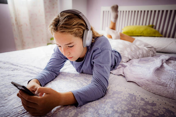 電話でヘッドフォンとテキストメッセージを使用するティーンエイジャーの女の子 - text messaging mobile phone teenagers only people ストックフォトと画像
