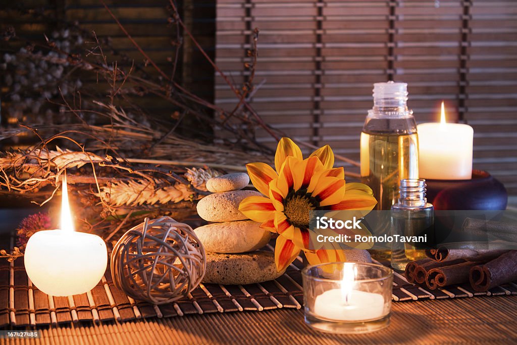 Pierres blanc, fleurs séchées, des bougies, huile, sur un petit tapis - Photo de Bougie libre de droits