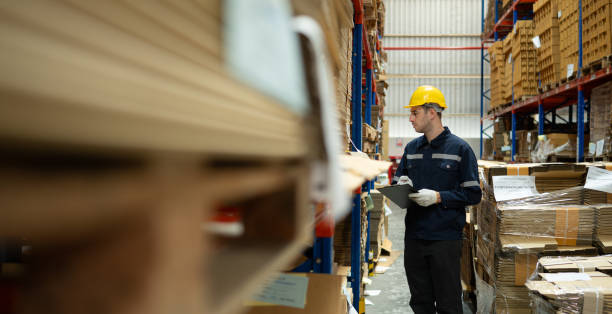 istock Young male warehouse worker checking stock in a warehouse. This is a large paper package storage and distribution warehouse. 1674274998