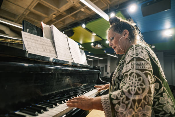 istock Senior woman playing piano on the stage 1674280127