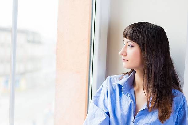 istock Woman in a blue shirt looking out the window 167430450