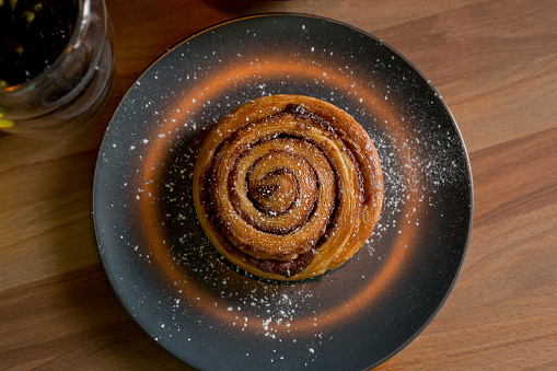 Cinnamon rolls on a black plate on a wooden table, top view