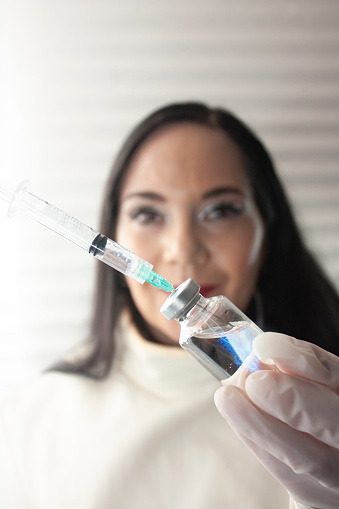 Woman doctor showing new syringe needle and vial first injection bottle first injection bottle DNA strand representing copy messenger RNA is observed