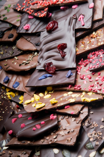 Heap of  chopped milk and dark chocolate bars with various delicious ingredients - rose, strawberry, japan tea, ananas, cranberries...