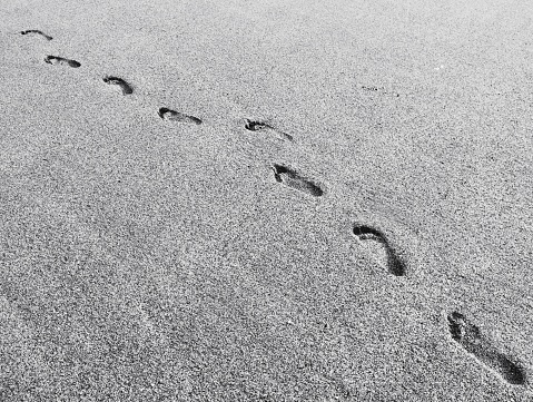 Representing meeting, separation or loneliness, two sets of footprints cross on the beach in the early morning.