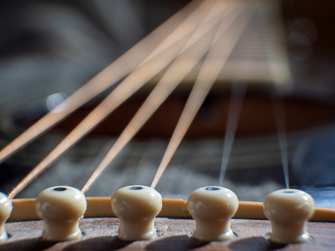 A close-up of the strings of an old acoustic guitar