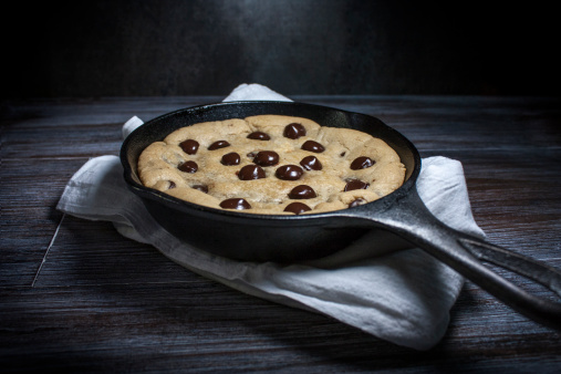 A hot chocolate chip cookie in a cast iron pan.