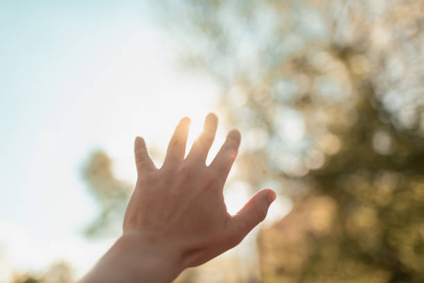 istock Hand reaching out touching the rays of sunlight. 1674396663