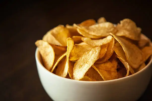 Crispy potato chips in white bowl