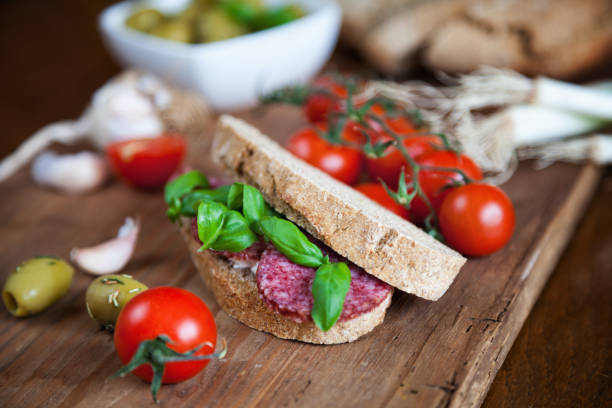 Sandwich with goat cheese, salami and basil.