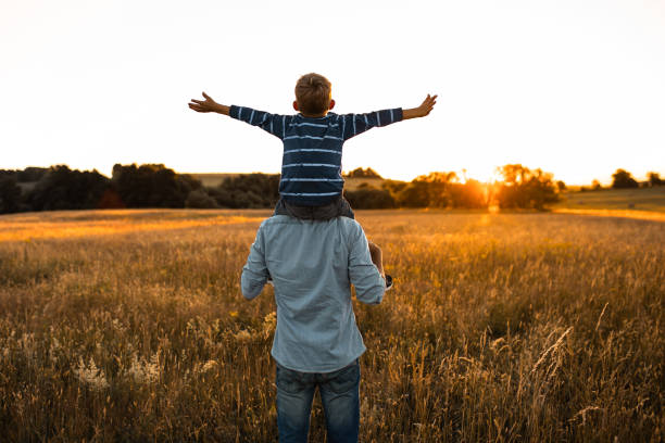 Father and son walking together in an open field feeling happy.