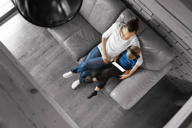 istock Mother and son relaxing on safe at home using tablet device. 1674406063