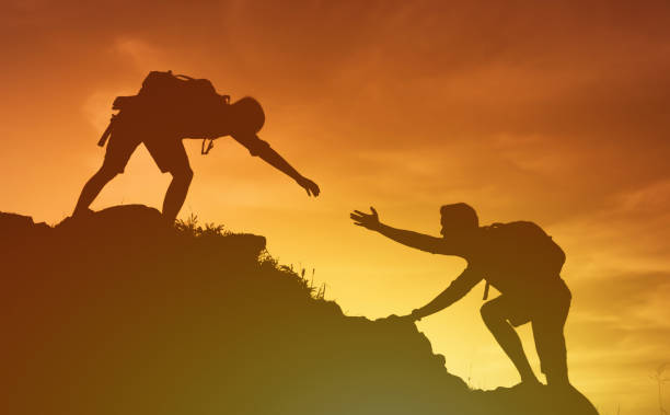 istock People helping each other hike up a mountain at sunrise. 1674407146
