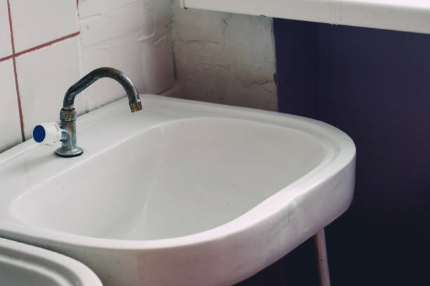 istock Bathroom white ceramic old sink with rusty water tap in public restroom 1674415481