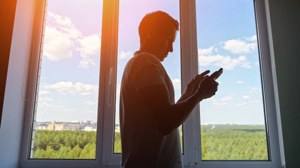 istock Male office worker walking to window scrolls social media 1674441099