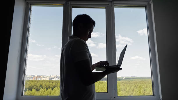 istock Male office worker standing near window scrolls social media 1674441105