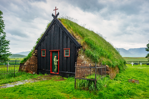 Child stands at the door of Vidimyrarkirkja turf church in Iceland