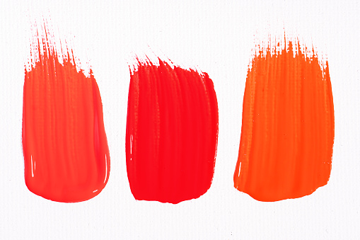 Three smears of different red paint swatch on white background. Bright red, red and light red samples of lip gloss, cosmetic product stroke or paint